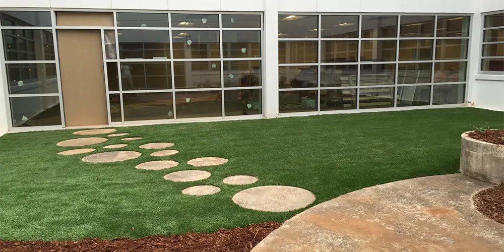 Creative office outdoor space with synthetic grass and circular stepping stones, combining functionality and design for a pleasant working environment.